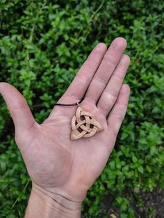 a hand holding a piece of wood in it's palm with a knot on it