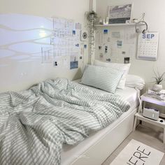 a bed sitting in a bedroom next to a wall with calendars on the walls