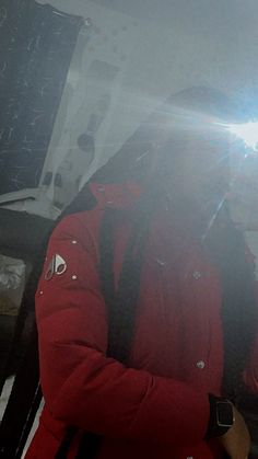 a man in red jacket standing next to a snowboard