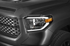 the front end of a gray truck with chrome grilles and lights on it's head