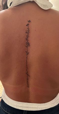 the back of a woman's lower back tattoo with flowers and words on it