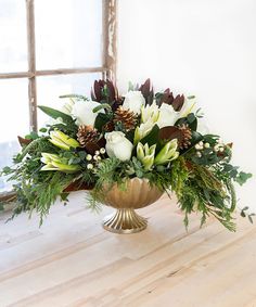 a gold vase filled with white flowers and greenery