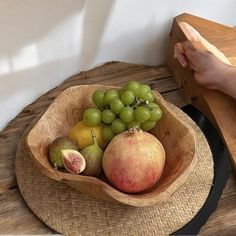 a wooden bowl filled with fruit on top of a table