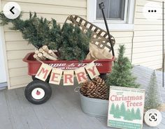 a red wagon filled with christmas trees sitting on top of a wooden floor next to a house