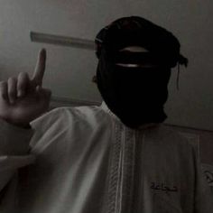 a man wearing a black mask making the peace sign with his fingers in front of him