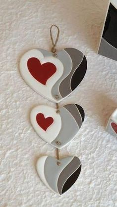 three heart shaped ornaments hanging from strings on a white surface with a box in the background