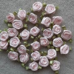 small pink roses with green stems on a gray surface, ready to be made into brooches