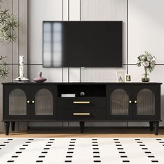 a living room with a black entertainment center and white rugs on the floor in front of a flat screen tv