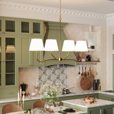 a kitchen filled with green cabinets and white counter tops next to a dining room table