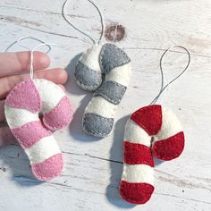 two handmade christmas ornaments are being held by someone's hands on a white wooden surface