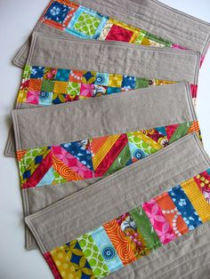 four quilted placemats sitting on top of each other with different colored strips