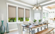 the dining room table is set with place settings for four people, and there are two vases on either side of the table