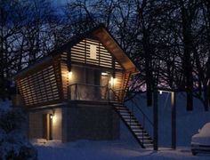 a small cabin in the snow at night with lights on and stairs leading up to it