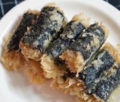 two pieces of sushi on a white plate next to a blue and black checkered table cloth