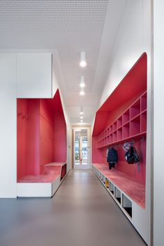 a long hallway with red and white shelvings on the walls, along with two benches