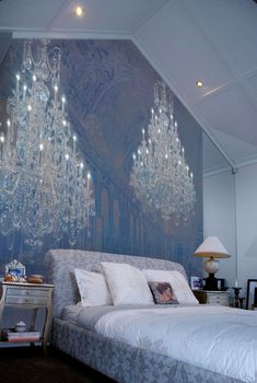 a bedroom with chandeliers hanging from the ceiling and a large bed in front of it