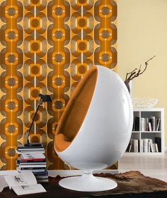 an orange and white chair sitting in front of a wall with circles on it's side