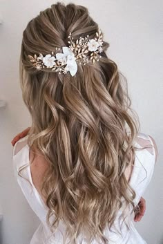 the back of a woman's head with long hair and flowers in her hair