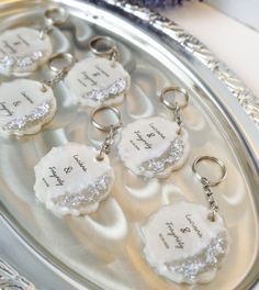 wedding keychains with names on them sitting on a silver tray next to flowers