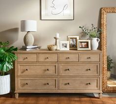 a dresser with pictures and plants on it