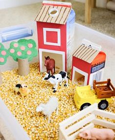 a toy farm with animals, horses and hay in the ground next to a red barn