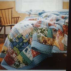 a bed covered with colorful quilts next to a chair and window in a room