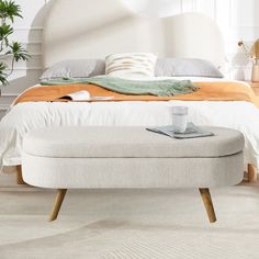 a bed with a white headboard and foot stool in front of it on top of a carpeted floor