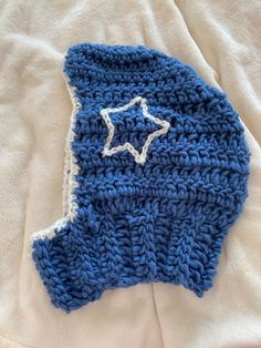 a blue and white crocheted hat laying on top of a bed