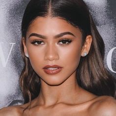 an image of a woman with long hair and brown eyeshadow wearing diamond earrings