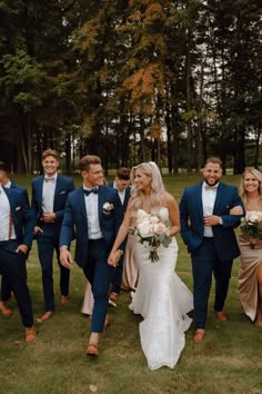 a bride and groom walking with their bridal party in the background at this wedding