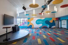 an empty room with brightly colored carpeting and colorful lights hanging from the ceiling above it