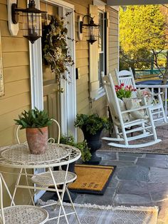 two rocking chairs and a table on the front porch