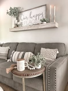 a living room with a gray couch and coffee table in front of a window that says our happy place