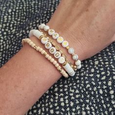 a person wearing three bracelets with shells on them