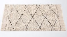 a white rug with black diamond shapes on the bottom and fringes in the middle