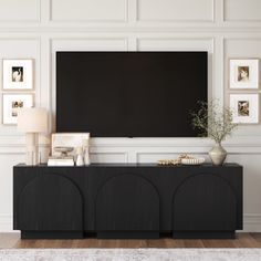 a black entertainment center with pictures on the wall and a flat screen tv above it