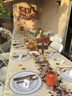 a table set for thanksgiving dinner with plates and silverware on it, along with a sign that says give thanks