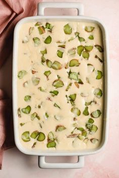 a casserole dish filled with white sauce and green sprouts on top