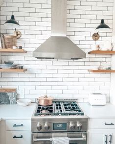 a stove top oven sitting inside of a kitchen next to wooden shelves and open shelving