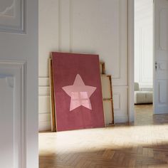 an empty room with a pink star on the wall and wood flooring in front of it