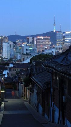 the city skyline is lit up at night, with buildings in the foreground and an alley way leading to it