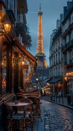 the eiffel tower is lit up at night, with tables and chairs outside