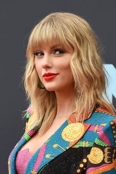 taylor swift at the cmt music awards wearing a colorful suit and red lip ring