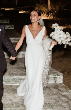 a bride and groom are walking down the steps holding hands with each other in front of them