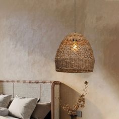 a wicker light hanging over a bed next to a vase with flowers on it