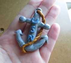 a hand holding a small blue and yellow anchor ring