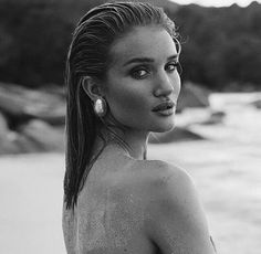 black and white photograph of a woman on the beach with water in the back ground