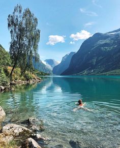 a person swimming in a lake surrounded by mountains