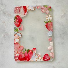 a square shaped glass plate with flowers and leaves painted on the bottom, sitting on a gray surface