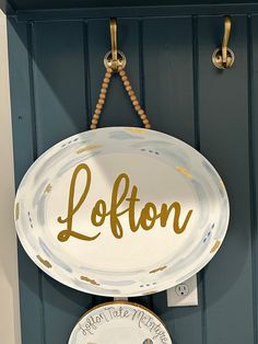 a sign hanging on the side of a blue door that says lofton above two plates